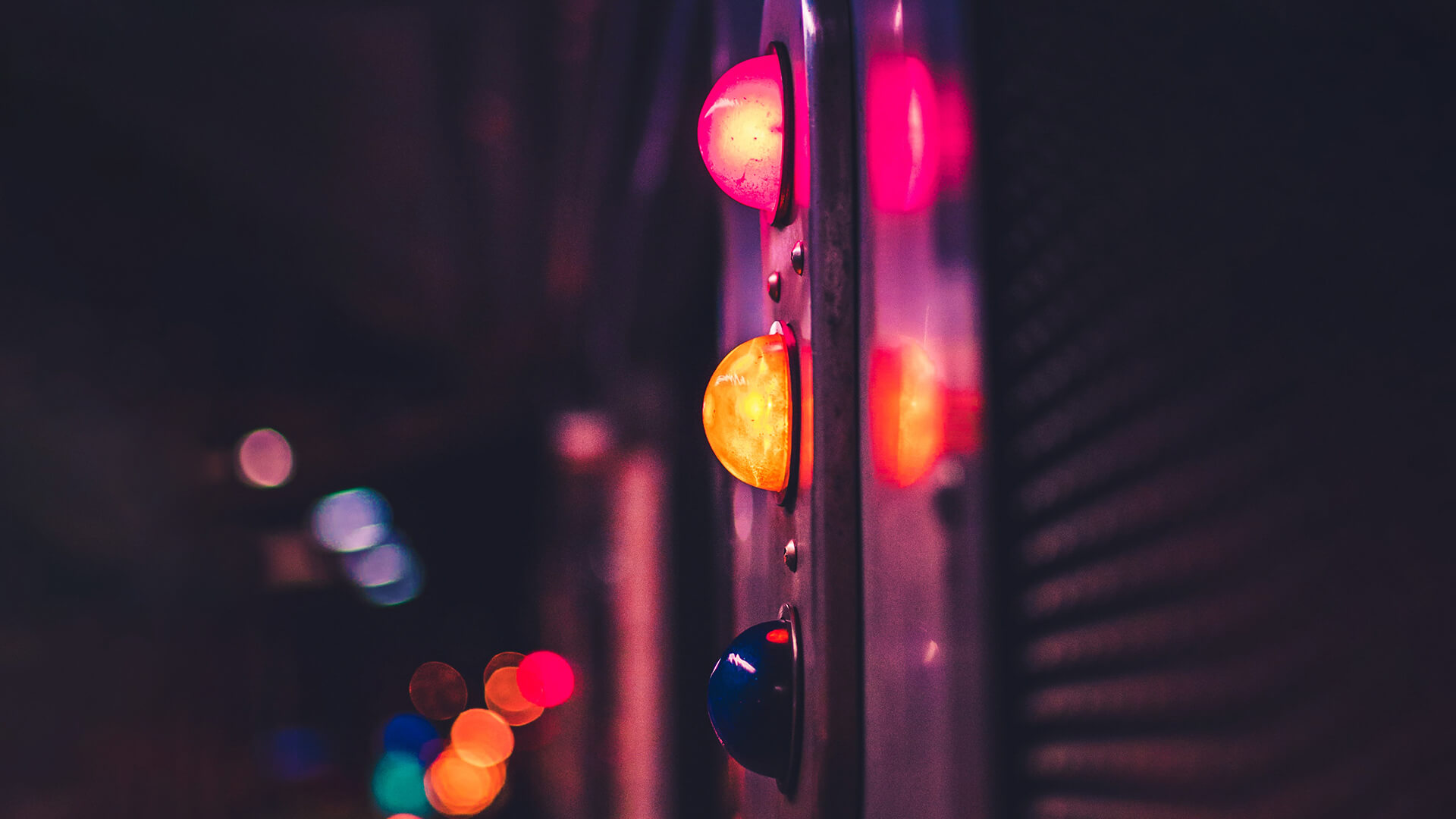 A traffic light with red and yellow lights on, on a dark street. 