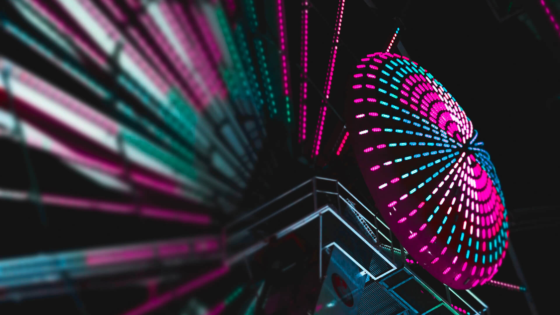 Ferris wheel up close with purple neon lights on it.