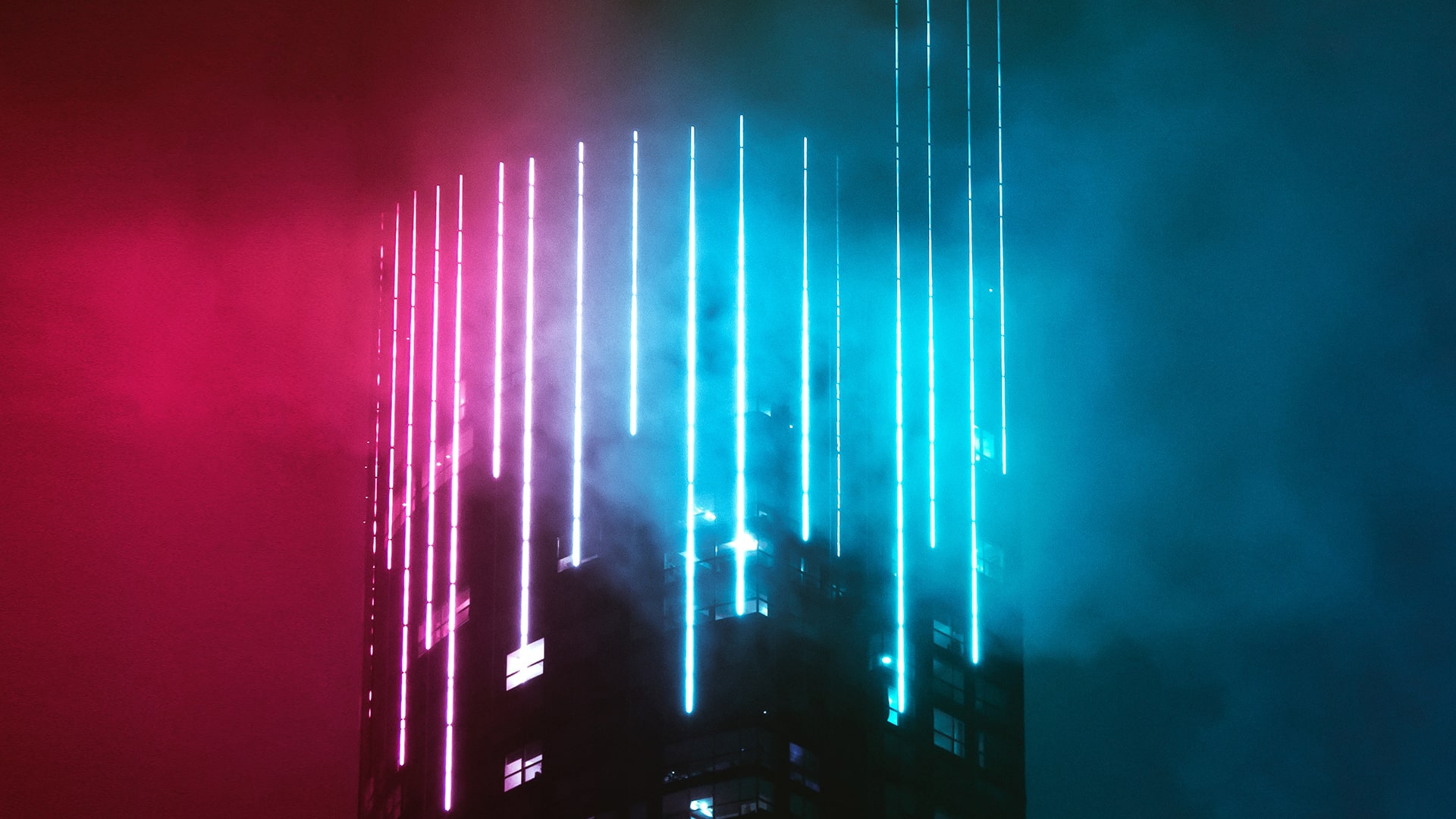 Apartment building at night, covered in bright red and blue fog.