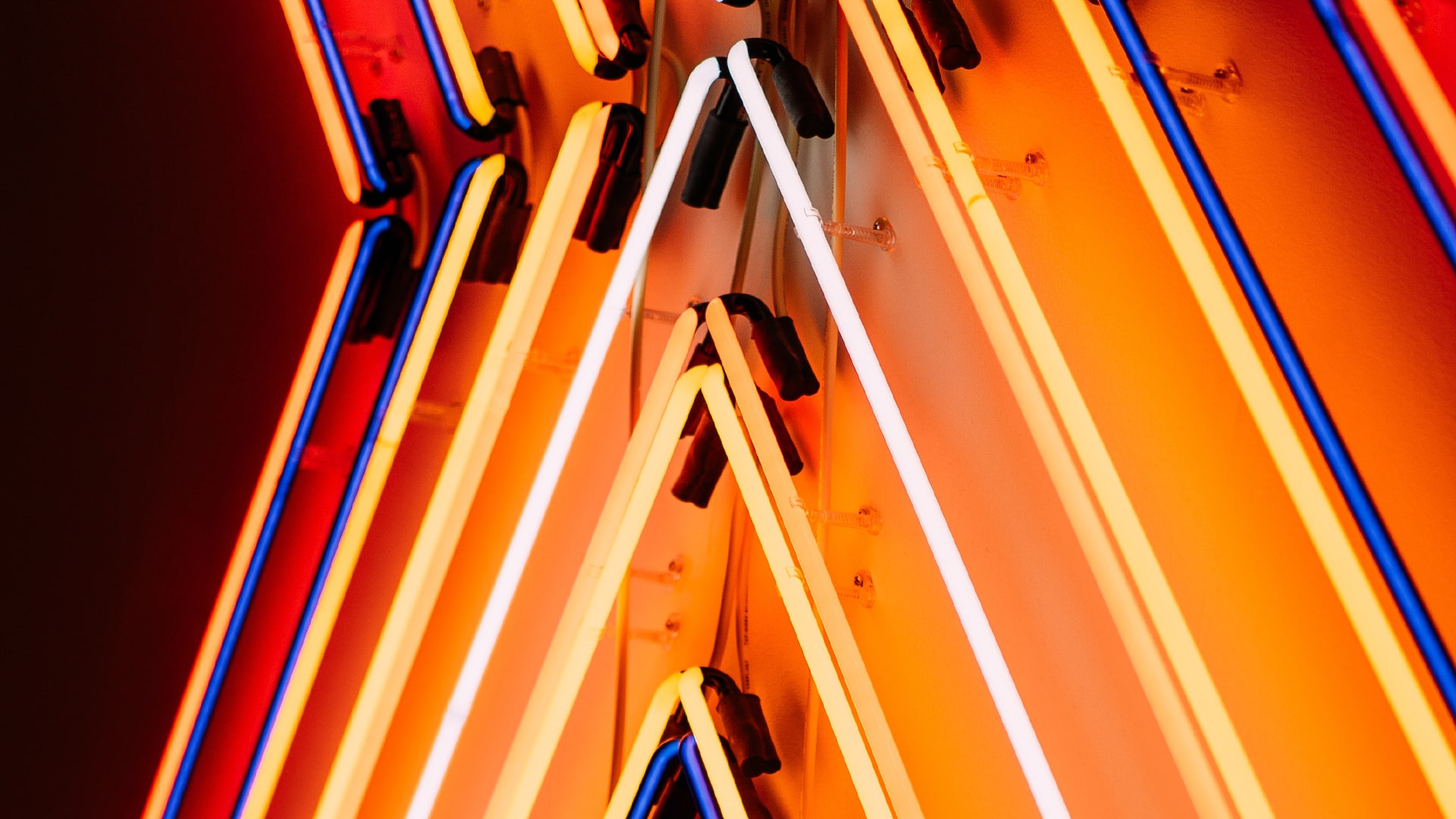 A yellow neon sight up close of a letter 'X'.